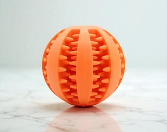 May include: An orange, textured dog toy in the shape of a ball. The ball has a series of raised, rounded ridges and small, pointed protrusions. The toy is designed for chewing and play.
