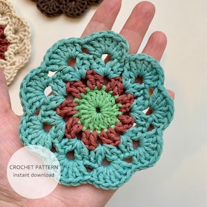 Könnte beinhalten: Eine türkisfarbene Häkelblume mit einem grünen und braunen Zentrum. Die Blume wird in einer Hand gehalten. Der Text "CROCHET PATTERN instant download" ist unter der Blume sichtbar.