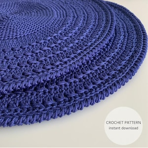 May include: A close-up of a circular, indigo blue crochet pattern. The crochet design features concentric circles with varying textures, including openwork and solid areas. The image includes the text "CROCHET PATTERN instant download".