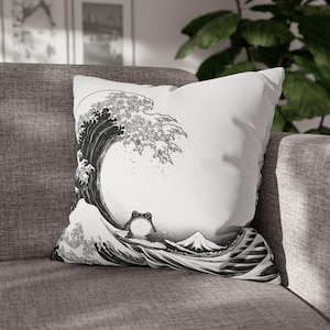 May include: White throw pillow featuring a black and white illustration of a large ocean wave with a frog in the foreground. The design is reminiscent of traditional Japanese art, with a mountain in the background.