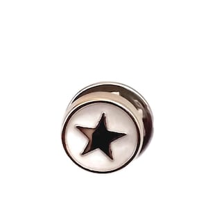 Può includere: Spilla da bavero argentata con un design a stella nera all'interno di un cerchio bianco. La spilla ha una finitura metallica lucida e un design classico e minimalista. La stella è centrata, creando un effetto accattivante.