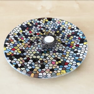 Op de afbeelding: Een ronde, zwart-witte schaal met een mozaïekpatroon. De schaal heeft een kleine, witte en zilveren ring in het midden.