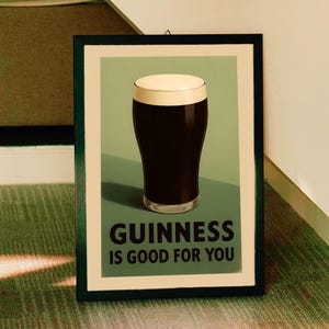 May include: A vintage-style poster with a green background featuring a glass of Guinness beer with a white head. The text on the poster reads "GUINNESS IS GOOD FOR YOU".