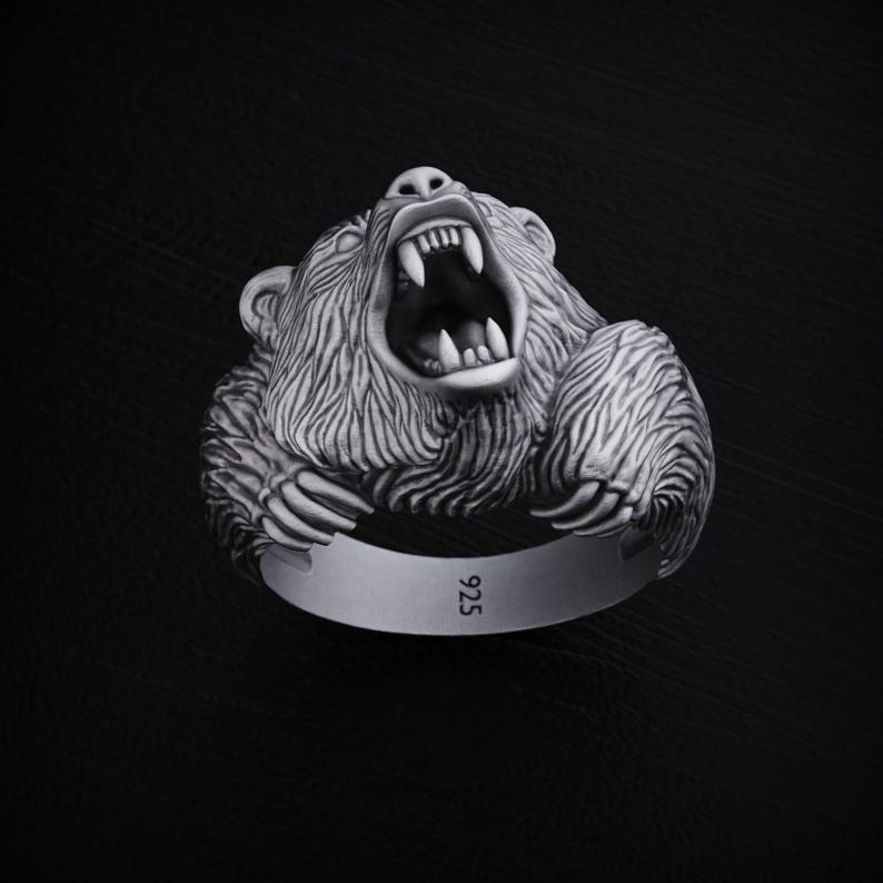 May include: A silver ring with a detailed, roaring bear head design. The ring is marked with "925" on the band.