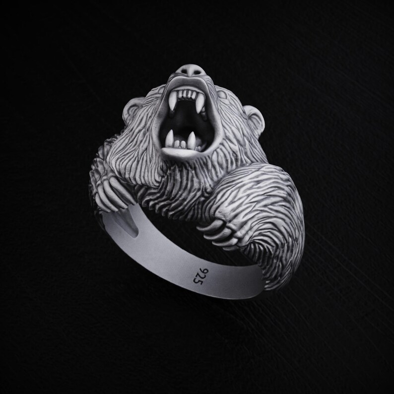 May include: A silver ring featuring a detailed, roaring bear head. The ring is marked with "925" on the band.