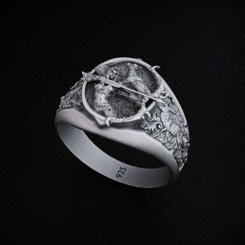 May include: A silver ring with a detailed design of a warrior holding a bow and arrow. The ring is marked with "925" on the inside band.