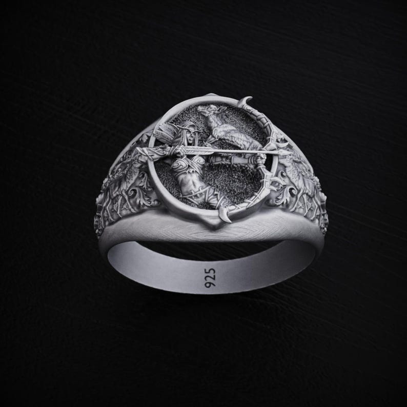 May include: A silver ring with a detailed design of a woman with a bow and arrow, a deer, and foliage. The ring is marked with the number "925".