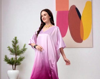 May include: A woman wearing a flowing, V-neck, ombre-dyed satin caftan in shades of pink and burgundy. The caftan is paired with matching pants and light-colored sandals. A gold-toned necklace and a black watch complete the look.