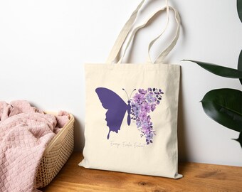 May include: A white tote bag with a purple butterfly silhouette and purple watercolor flowers. The text "Every End is a Beginning" is printed on the bag.