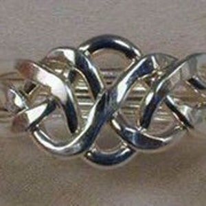 Puede incluir: Un anillo de puzzle de plata con un dise&ntilde;o complejo entrelazado. El anillo est&aacute; hecho de m&uacute;ltiples bandas entrelazadas que crean un patr&oacute;n &uacute;nico e intrincado.