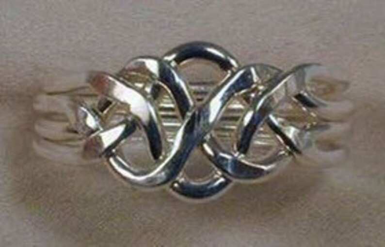 Puede incluir: Un anillo de puzzle de plata con un dise&ntilde;o complejo entrelazado. El anillo est&aacute; hecho de m&uacute;ltiples bandas entrelazadas que crean un patr&oacute;n &uacute;nico e intrincado.