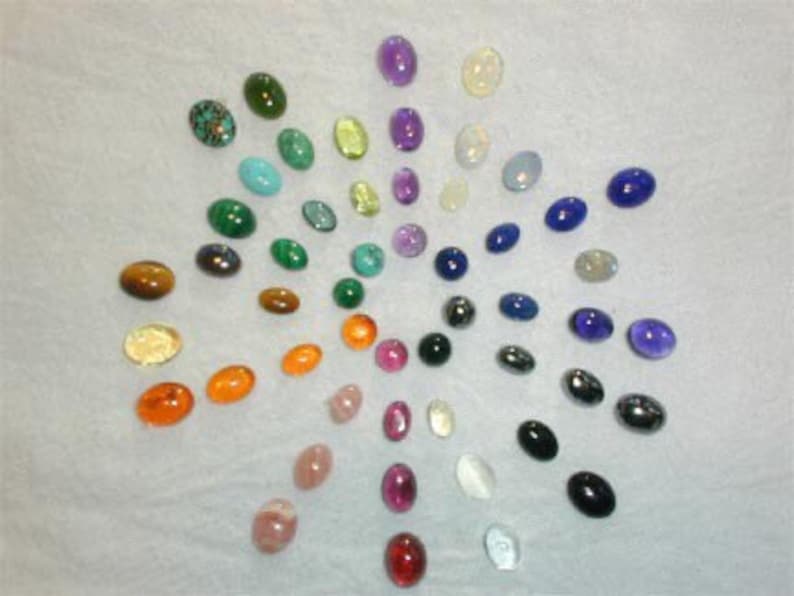 Puede incluir: Una colecci&oacute;n de piedras preciosas ovaladas dispuestas en un patr&oacute;n circular. Las piedras preciosas son de varios colores, incluidos el verde, el azul, el morado, el rojo, el naranja, el amarillo y el marr&oacute;n.