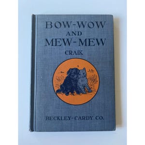 May include: Vintage hardcover book titled "BOW-WOW AND MEW-MEW" by Craik. The cover is a textured blue with an orange circular illustration of a dog and cat. The publisher's name, BECKLEY-CARDY CO., is printed at the bottom.