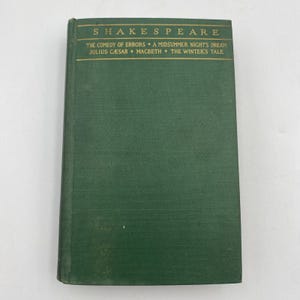 May include: A hardcover book with a green cover featuring gold lettering that reads "SHAKESPEARE." The book's title includes "THE COMEDY OF ERRORS," "A MIDSUMMER NIGHT'S DREAM," "JULIUS CAESAR," "MACBETH," and "THE WINTER'S TALE."