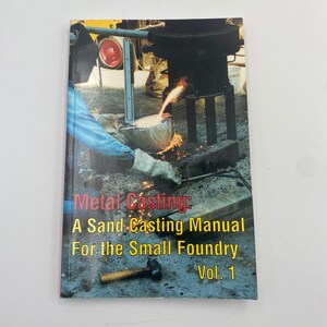 May include: A book titled "Metal Casting: A Sand Casting Manual For the Small Foundry Vol. 1" with a photo of metal casting in progress. The cover features a worker pouring molten metal, sparks, and a hammer.