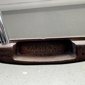 Puede incluir: Putter de golf Ping MLT vintage con cabeza marrón y varilla plateada. La cabeza del putter tiene el texto "KARSTEN CO. PHOENIX, ARIZ. 85028 MADE IN U.S.A." y "BALL-NAMIC" y "PING MLT".