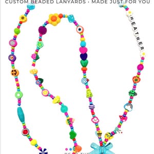 May include: A multi-colored beaded lanyard featuring various shapes including flowers, hearts, fruits, and smiley faces. The text "REAL CUSTOMER DESIGNS CUSTOM BEADED LANYARDS MADE JUST FOR YOU" is visible at the top, and the name "HEATHER" is spelled out in white letter beads.