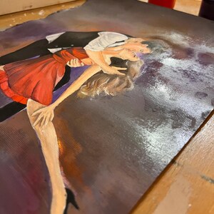 May include: An original painting depicts a couple dancing. The woman wears a red dress, and the man is in a black suit with a white shirt. The artwork is on a dark background with visible brushstrokes and paint splatters, suggesting an artistic process.