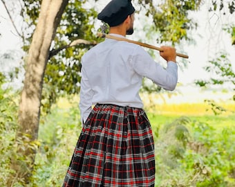 May include: A person wearing a black beret, white shirt, and a black, red, and white plaid kilt. The image includes the text "Available IN 50+ Tartans". The kilt is knee-length and worn with white socks and black boots.