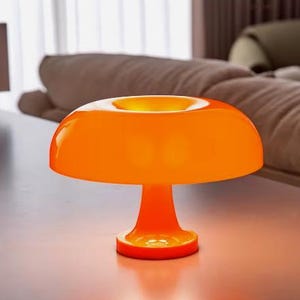 May include: Orange table lamp with a wide, round, mushroom-shaped shade and a short, round base.