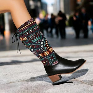 May include: Black leather boots with a colorful patterned fabric shaft. The boots have a lace-up detail on the back and a block heel.