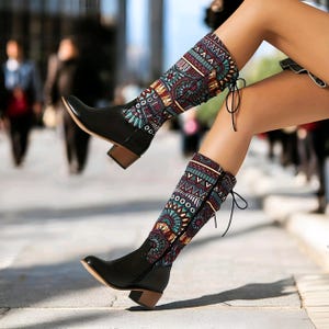 May include: Black leather boots with a patterned fabric shaft. The pattern is a mix of geometric shapes and floral designs in shades of red, blue, green, and yellow.