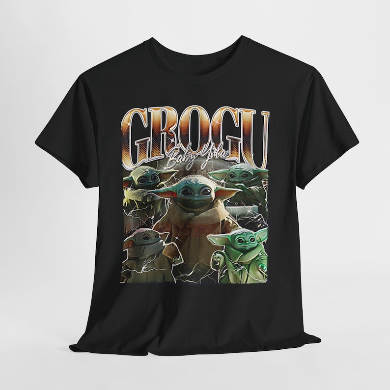 Può includere: T-shirt nera con una grafica di Grogu, noto anche come Baby Yoda, da The Mandalorian. Il design include più immagini di Grogu e il testo "GROGU Baby Yoda" in stile retrò.