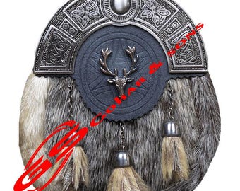 Può includere: Un tradizionale sporran per kilt scozzese con un cantle argentato con nodi celtici e un design ovale centrale. Lo sporran ha un fronte in pelle grigio scuro con un emblema di cervo e un corpo in pelliccia con tre nappe decorative.
