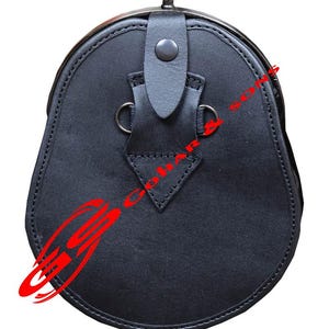 K&ouml;nnte beinhalten: Ein schwarzer Leder-Sporran, eine traditionelle schottische Tasche, mit abgerundeter Unterseite und Metallverschluss. Er hat einen Klappenverschluss mit Knopf und zwei Metallringen. Das Leder ist an den R&auml;ndern gen&auml;ht.