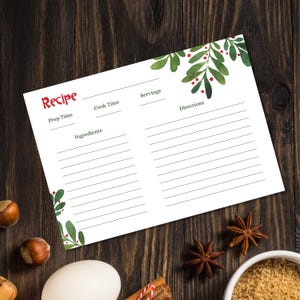 Puede incluir: Tarjeta de receta blanca con la palabra «Receta» en rojo. Tiene líneas para el tiempo de preparación, el tiempo de cocción, las porciones, los ingredientes y las instrucciones. Hojas verdes de acuarela y bayas rojas decoran las esquinas.