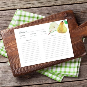 Puede incluir: Una tarjeta de receta blanca con ilustraciones de pera se encuentra sobre una tabla de cortar de madera, encima de un paño a cuadros verde y blanco. La tarjeta tiene secciones para el tiempo de preparación, el tiempo de cocción, los ingredientes, las porciones y las instrucciones.