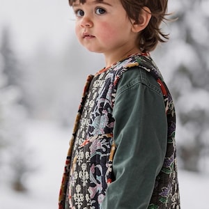 Peut inclure: Un enfant porte un gilet matelassé à motifs floraux noirs, roses et bleus, associé à une chemise verte à manches longues. L'arrière-plan est une scène hivernale floue. Les mesures du gilet sont en centimètres.
