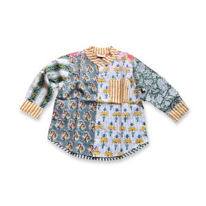 May include: A long-sleeved shirt with a patchwork design. The shirt features a variety of floral and striped patterns in shades of green, yellow, and white. It has a small pocket on the chest and striped cuffs.