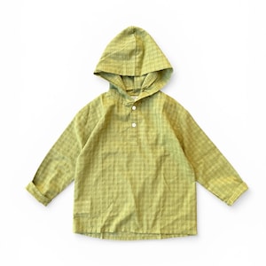 Puede incluir: Una camisa con capucha verde claro con mangas largas. La camisa presenta un escote abotonado y un estampado de cuadros. La tela parece ligera, adecuada para climas cálidos. La capucha es una característica destacada.