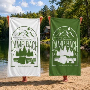 May include: Two rectangular beach towels, one white with green ink and one green with white ink, featuring a graphic of mountains, pine trees, a tent, a campfire, and the text "2025 Katie's Bachelorette CAMP BACH BRECKENRIDGE, CO" in a circular frame.