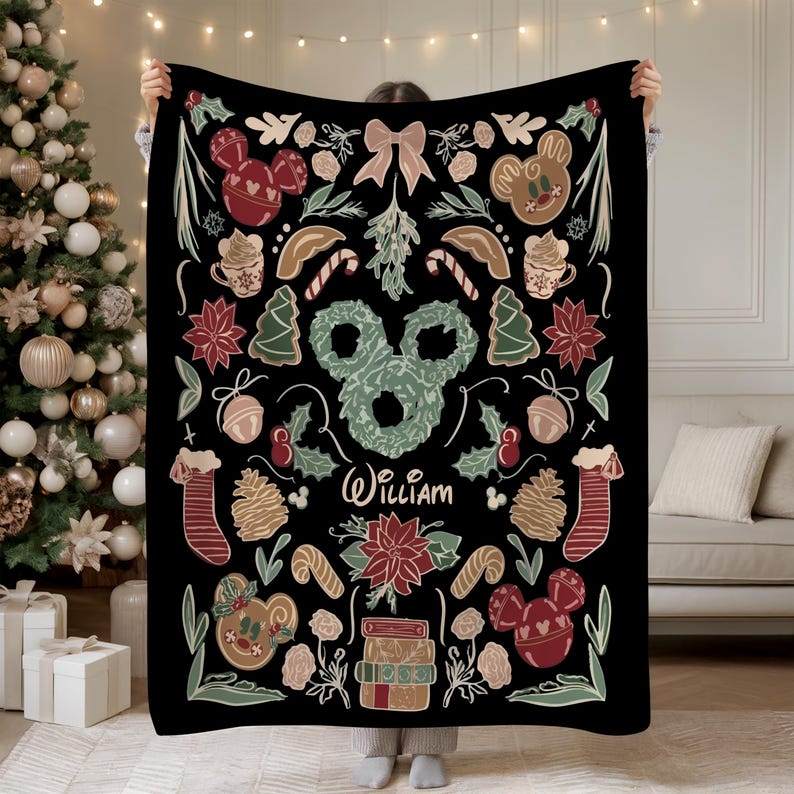 Puede incluir: Manta negra con tem&aacute;tica navide&ntilde;a y dise&ntilde;o festivo. Presenta hombres de jengibre, adornos con forma de Mickey Mouse, bastones de caramelo y flores de Nochebuena. El nombre "William" est&aacute; escrito en cursiva.