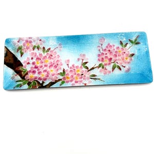 May include: Rectangular decorative tray with a blue background and a painted cherry blossom design. The blossoms are pink with yellow centres, and the branches are brown. The tray is approximately 30 cm long.