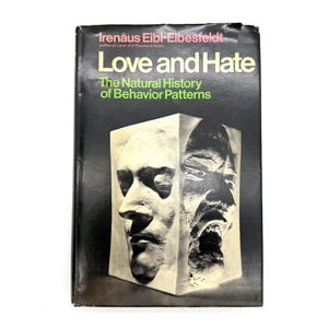 May include: A hardcover book titled Love and Hate: The Natural History of Behavior Patterns by Irenäus Eibl-Eibesfeldt. The black cover features a white graphic of a sculpted block showing two contrasting human faces, one calm and one aggressive.