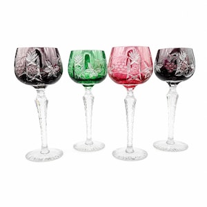 May include: Four coloured wine glasses with etched designs. The glasses are in shades of purple, green, and red. Each glass has a clear, textured stem and base. The etched designs include grape clusters and leaves.