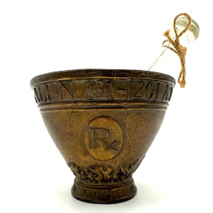 Dekorativer Mörser & Stößel - Claudius Galen Tribut, bronzefarbener Mörser mit Glaskolben, Inschrift „Secundum Artem“.