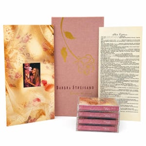Könnte beinhalten: Eine Sammlung von Barbra Streisand-Erinnerungsstücken, darunter ein Fotoalbum, ein Buch mit Rosenmuster und Musikkassetten aus den 60er, 70er und 80er Jahren. Das Fotoalbum zeigt ein Bild von Barbra Streisand.