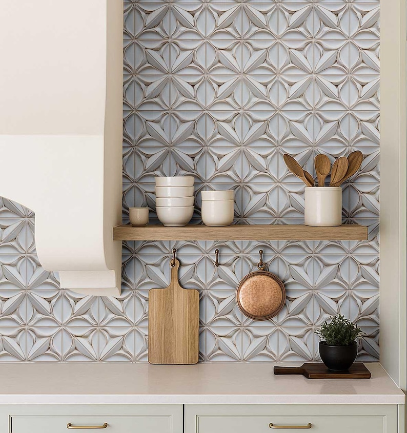 May include: A kitchen scene featuring a backsplash of patterned, light blue and white tiles. A wooden shelf holds white bowls and a ceramic utensil holder with wooden spoons. A wooden cutting board and copper pan hang below.