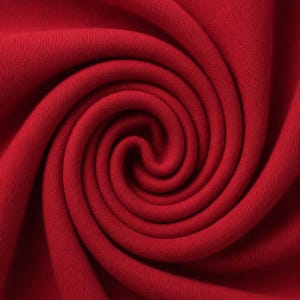 May include: A deep red fabric with a fine, uniform knit texture arranged in a tight, central spiral swirl. The material displays consistent colour saturation throughout, with subtle shadows highlighting the folds and depth of the circular pattern.