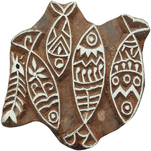 May include: A brown wooden block with a design of four white fish. The fish have various patterns, including zigzags, lines, and circles.