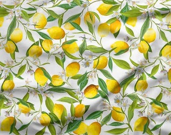 May include: A white fabric with a repeating pattern of yellow lemons, green leaves, and small white flowers. The lemons are in various stages of ripeness, and the leaves are a vibrant green. The design is detailed and realistic.