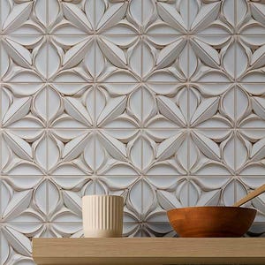 May include: White ceramic wall tiles with a repeating floral pattern. A small, beige, ribbed ceramic cup and a wooden bowl are on a wooden shelf. A wooden spoon rests in the bowl.