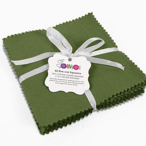May include: A stack of 40 pre-cut 5 x 5 inch green cotton squares, tied with a white ribbon and a label that reads "DIMOI 40 Pre-cut Squares 100% Cotton Charm Squares 5" x 5" Inches Squares Specially designed for quilting and are also perfect for any sewing and crafting projects, from apparel to home decor."