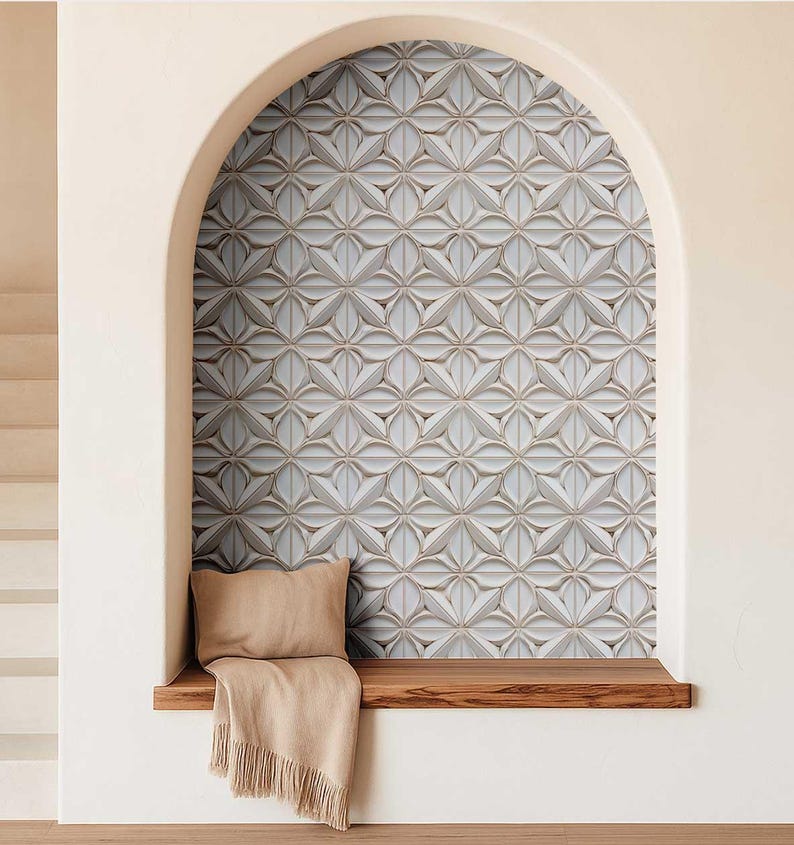 May include: A decorative wall panel with a repeating floral pattern in shades of white, gray, and beige. The panel is set within an arched alcove, with a wooden bench, a beige pillow, and a fringed throw. The overall aesthetic is modern and elegant.