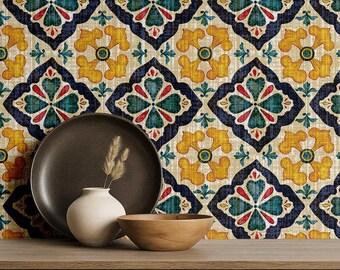 Puede incluir: Una composición decorativa con un plato marrón oscuro, un pequeño jarrón blanco con hierba seca y un cuenco de madera sobre una superficie de madera. El fondo muestra un papel pintado estampado con diseños florales azules, amarillos y rojos.