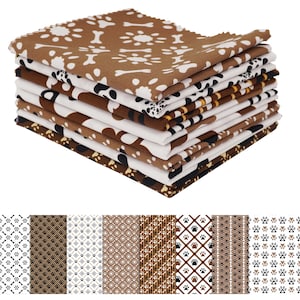 May include: A stack of patterned fabric squares featuring dog-themed designs. The fabrics display paw prints, bones, and other pet-related motifs in brown, white, and black. The fabrics are stacked neatly, showcasing various patterns.